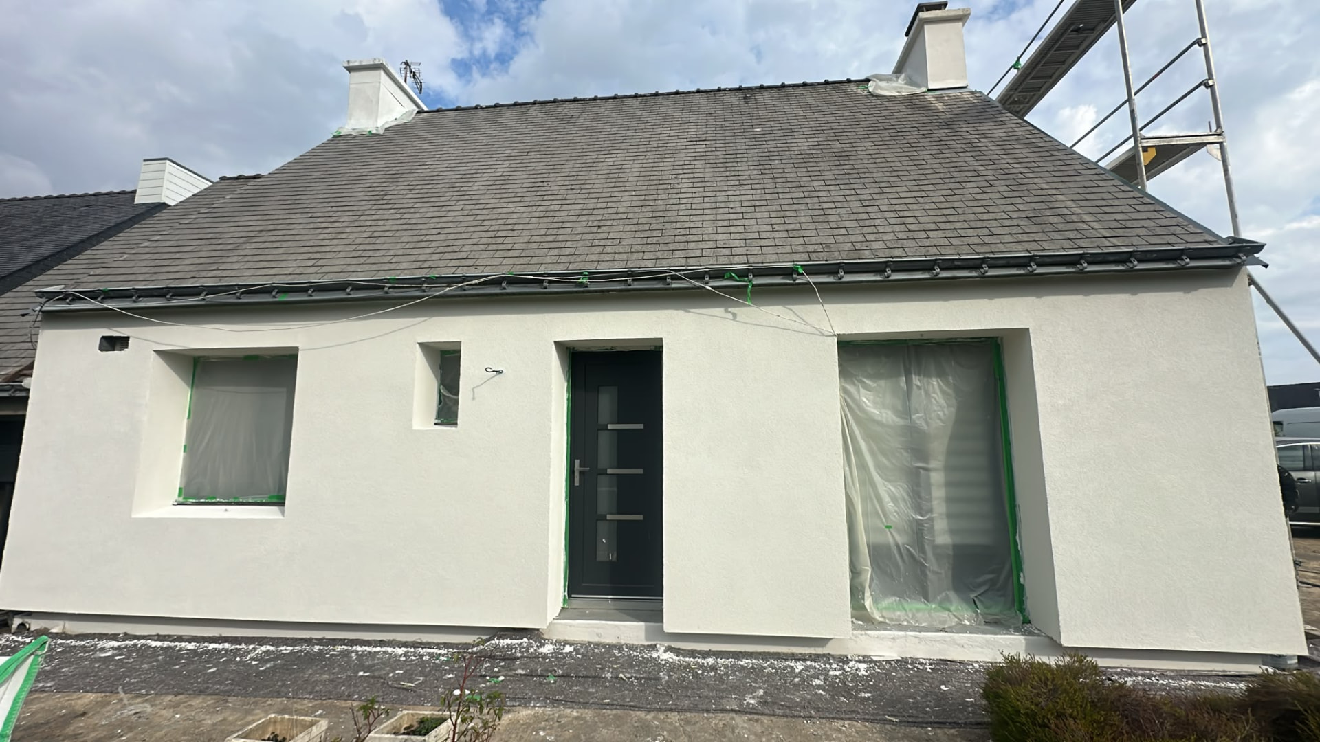Chantier dans le Morbihan — façade avant en finition enduit blanc crème, ouvertures protégées